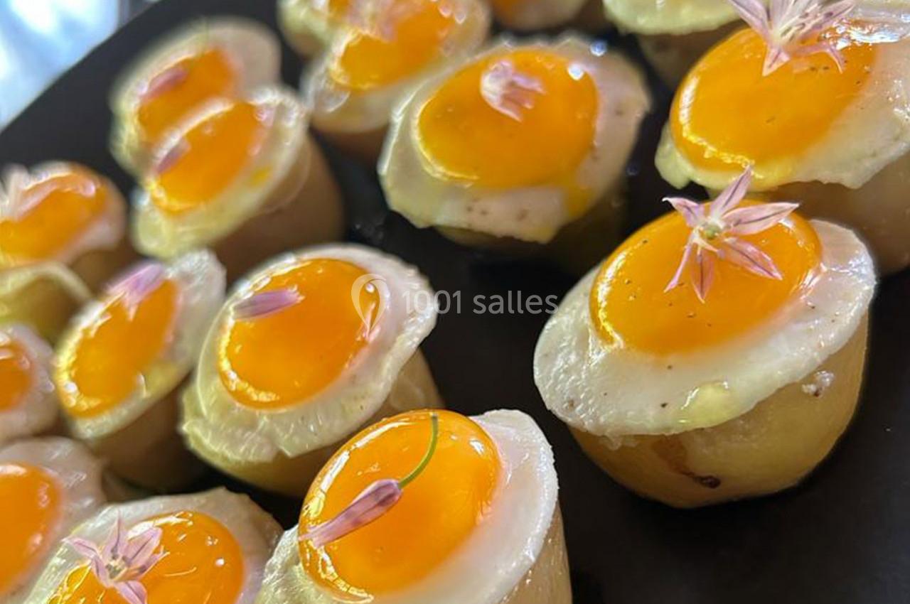 Petites bouchées de pommes de terre garnies d'œufs de caille au plat et décorées de fleurs comestibles.