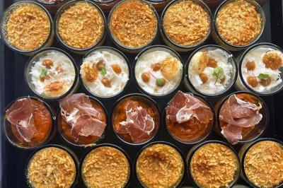 Assortiment de bouchées gastronomiques sur une planche en bois, incluant tartes aux légumes et poissons garnis.