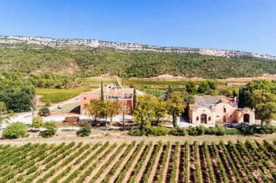 Salle de réception lumineuse avec murs en pierre, tables décorées de fleurs colorées et chandeliers suspendus.