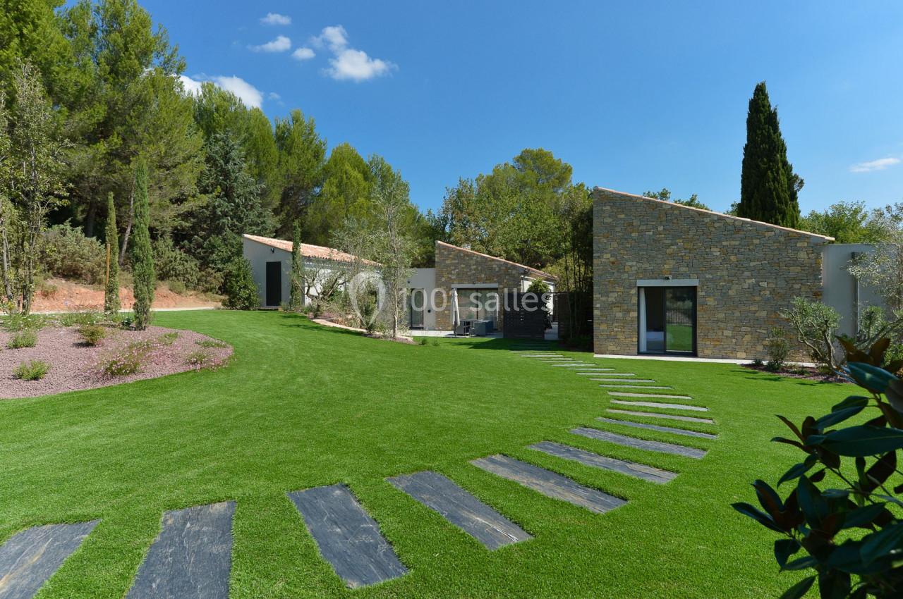Chemin en dalles menant à des maisons modernes entourées de pelouses et d'arbres dans un cadre naturel.