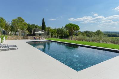 Salle de réception lumineuse avec murs en pierre, tables décorées de fleurs colorées et chandeliers suspendus.