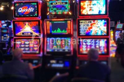 Salle de restaurant moderne avec des tables dressées, des chaises orange et un éclairage chaleureux.