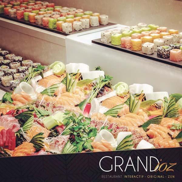 Plateau de sushis variés et colorés avec des tranches de poisson cru, légumes et herbes, présenté sur un buffet.