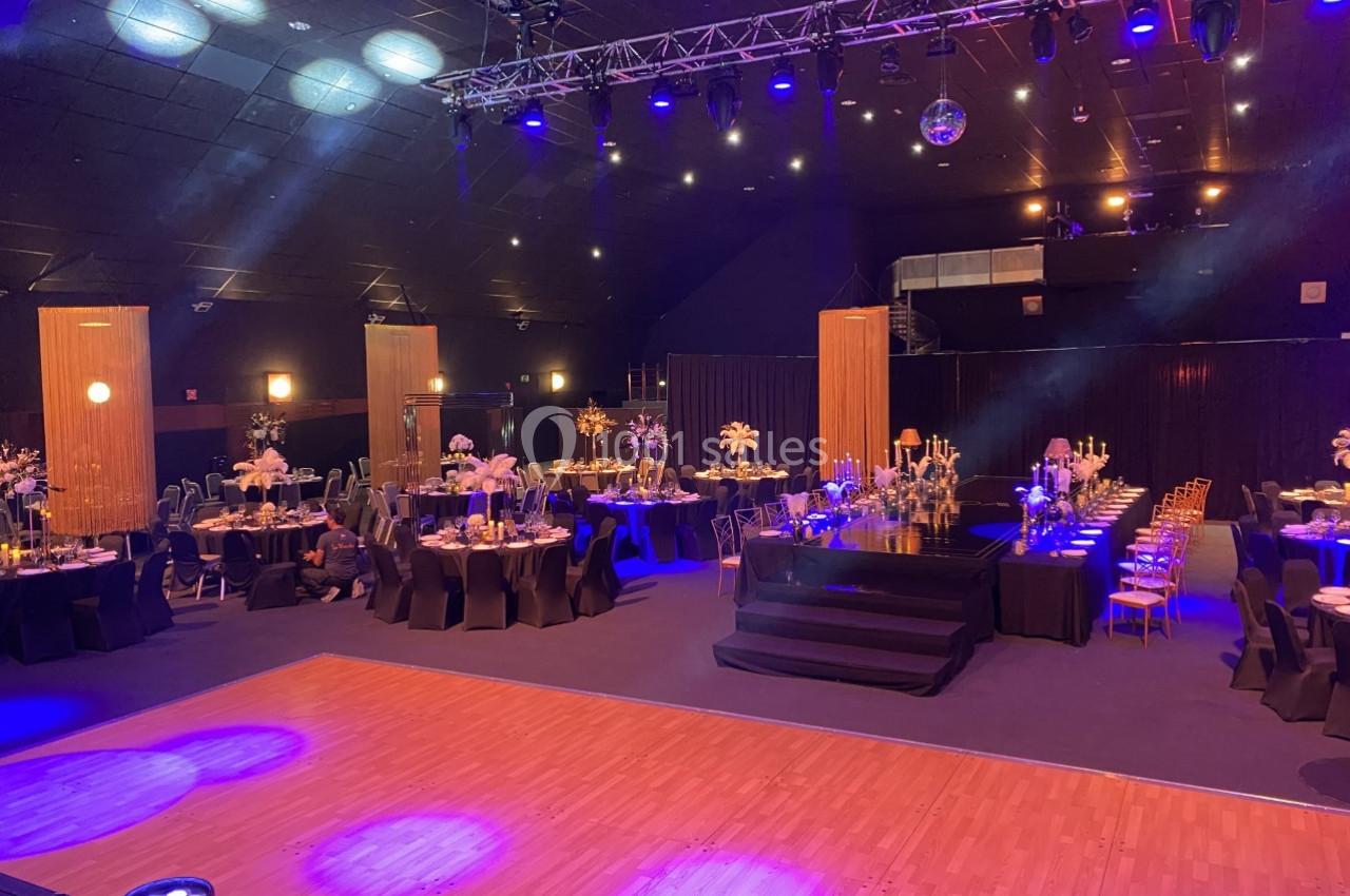 Salle de réception décorée avec des tables élégantes, éclairage tamisé et piste de danse en bois.