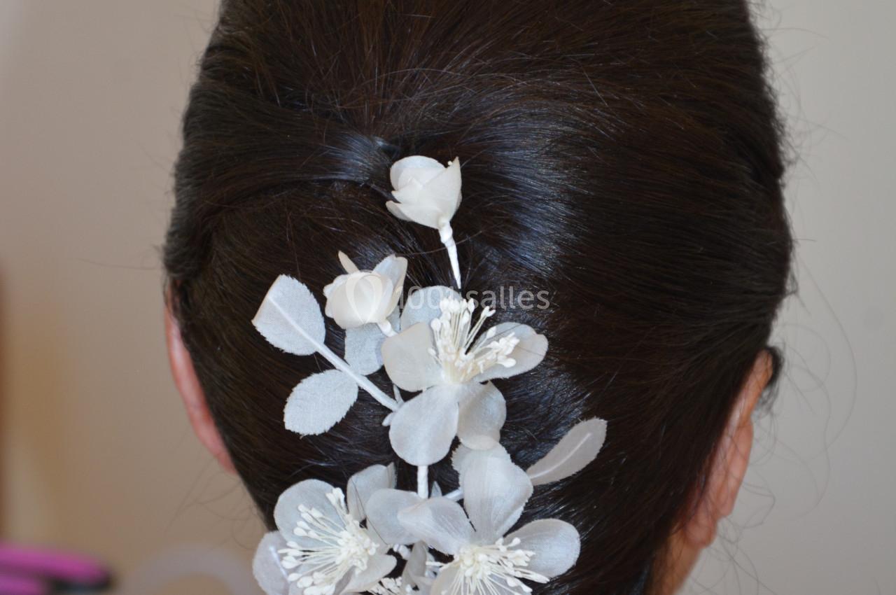 Chignon brun orné de fleurs blanches décoratives en tissu, vu de dos.