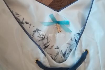 Mannequin vêtu d'une robe en dentelle blanche avec un voile noir couvrant la tête, devant une porte en bois clair.