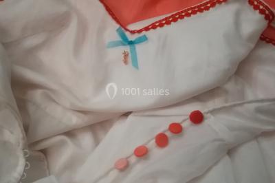 Mannequin vêtu d'une robe en dentelle blanche avec un voile noir couvrant la tête, devant une porte en bois clair.