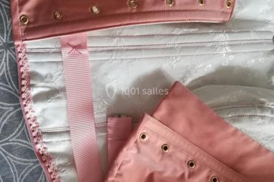 Mannequin vêtu d'une robe en dentelle blanche avec un voile noir couvrant la tête, devant une porte en bois clair.