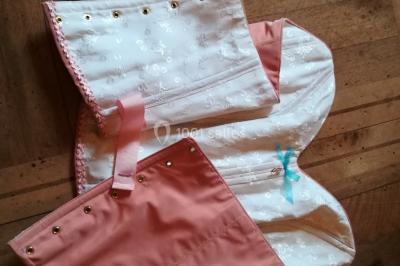 Mannequin vêtu d'une robe en dentelle blanche avec un voile noir couvrant la tête, devant une porte en bois clair.