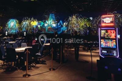Salle de casino avec machines à sous, tables de jeu et décorations lumineuses évoquant des feux d'artifice.
