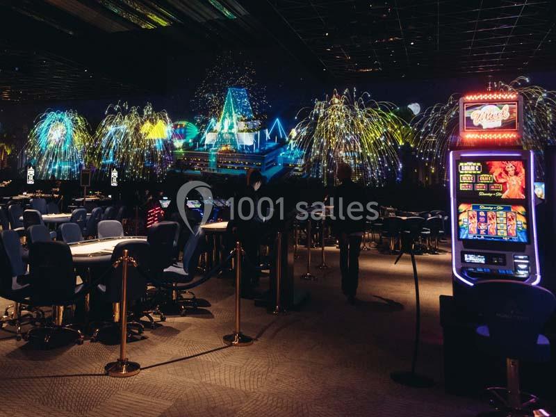 Salle de casino avec machines à sous, tables de jeu et décorations lumineuses évoquant des feux d'artifice.
