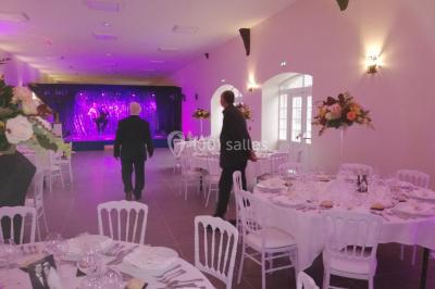 Canapé doré avec assise blanche devant un décor floral et un rideau blanc, éclairé par des appliques murales.