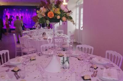 Canapé doré avec assise blanche devant un décor floral et un rideau blanc, éclairé par des appliques murales.