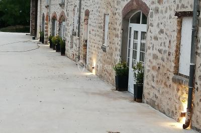 Canapé doré avec assise blanche devant un décor floral et un rideau blanc, éclairé par des appliques murales.