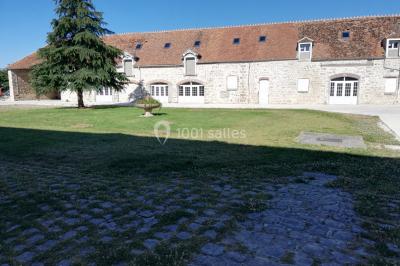 Canapé doré avec assise blanche devant un décor floral et un rideau blanc, éclairé par des appliques murales.