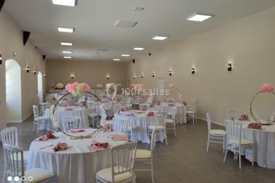 Canapé doré avec assise blanche devant un décor floral et un rideau blanc, éclairé par des appliques murales.