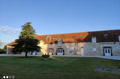 Canapé doré avec assise blanche devant un décor floral et un rideau blanc, éclairé par des appliques murales.