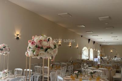 Canapé doré avec assise blanche devant un décor floral et un rideau blanc, éclairé par des appliques murales.