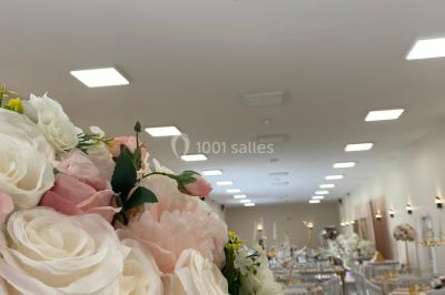 Canapé doré avec assise blanche devant un décor floral et un rideau blanc, éclairé par des appliques murales.