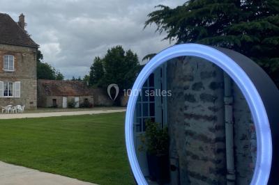 Canapé doré avec assise blanche devant un décor floral et un rideau blanc, éclairé par des appliques murales.