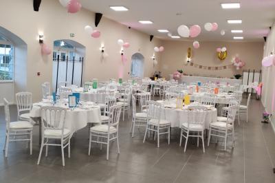 Canapé doré avec assise blanche devant un décor floral et un rideau blanc, éclairé par des appliques murales.