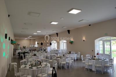 Canapé doré avec assise blanche devant un décor floral et un rideau blanc, éclairé par des appliques murales.