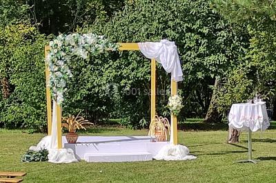 Canapé doré avec assise blanche devant un décor floral et un rideau blanc, éclairé par des appliques murales.