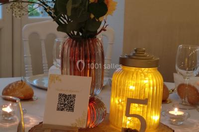 Canapé doré avec assise blanche devant un décor floral et un rideau blanc, éclairé par des appliques murales.