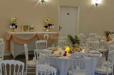 Canapé doré avec assise blanche devant un décor floral et un rideau blanc, éclairé par des appliques murales.