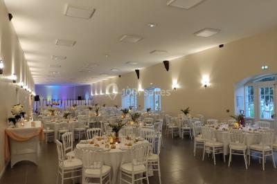 Canapé doré avec assise blanche devant un décor floral et un rideau blanc, éclairé par des appliques murales.