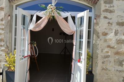 Canapé doré avec assise blanche devant un décor floral et un rideau blanc, éclairé par des appliques murales.