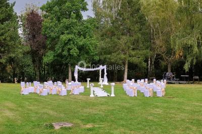 Canapé doré avec assise blanche devant un décor floral et un rideau blanc, éclairé par des appliques murales.