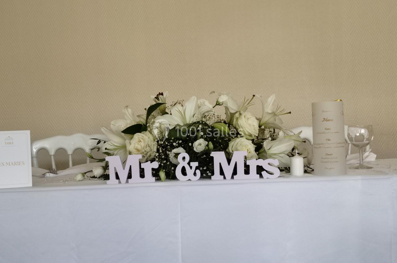 Décoration de table de mariage avec des fleurs blanches, des bougies et une inscription ’Mr & Mrs’.