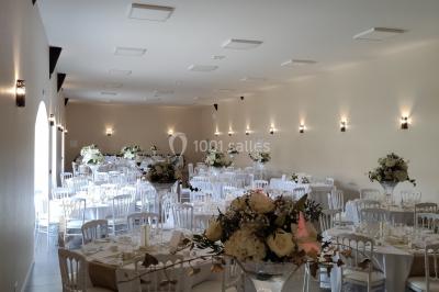 Canapé doré avec assise blanche devant un décor floral et un rideau blanc, éclairé par des appliques murales.