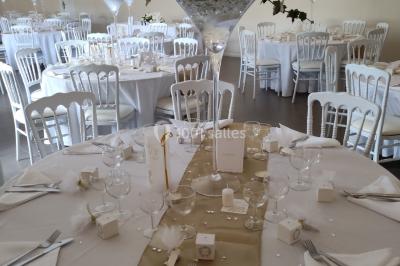 Canapé doré avec assise blanche devant un décor floral et un rideau blanc, éclairé par des appliques murales.