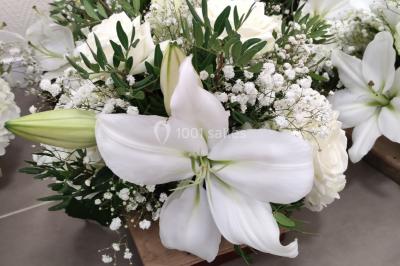 Canapé doré avec assise blanche devant un décor floral et un rideau blanc, éclairé par des appliques murales.