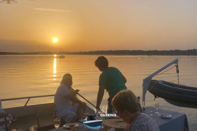 Mobilier en rotin noir avec coussins blancs sur une terrasse en bois couverte, vue sur l'extérieur urbain.