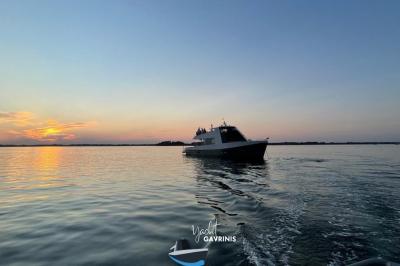 Mobilier en rotin noir avec coussins blancs sur une terrasse en bois couverte, vue sur l'extérieur urbain.