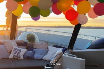 Mobilier en rotin noir avec coussins blancs sur une terrasse en bois couverte, vue sur l'extérieur urbain.