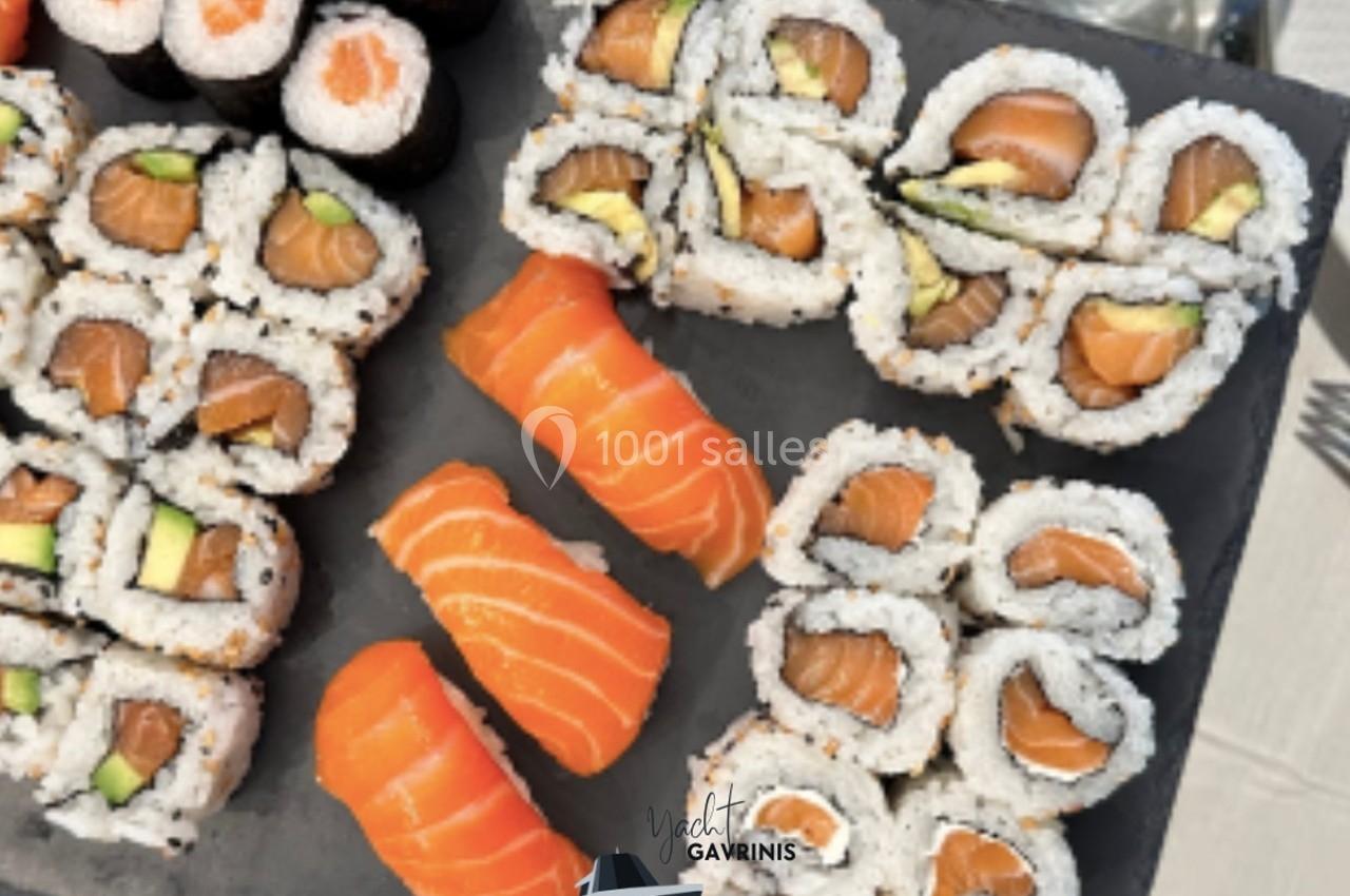 Assortiment de sushis et makis au saumon et à l'avocat présentés sur un plateau noir.