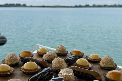 Mobilier en rotin noir avec coussins blancs sur une terrasse en bois couverte, vue sur l'extérieur urbain.