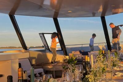 Mobilier en rotin noir avec coussins blancs sur une terrasse en bois couverte, vue sur l'extérieur urbain.
