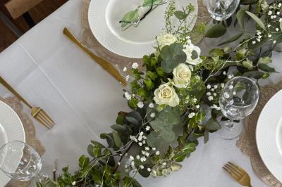 Mobilier en rotin noir avec coussins blancs sur une terrasse en bois couverte, vue sur l'extérieur urbain.