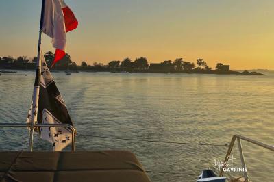 Mobilier en rotin noir avec coussins blancs sur une terrasse en bois couverte, vue sur l'extérieur urbain.