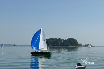 Mobilier en rotin noir avec coussins blancs sur une terrasse en bois couverte, vue sur l'extérieur urbain.