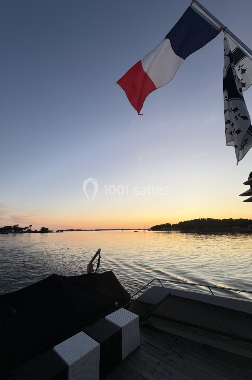 Drapeaux français et breton flottant au-dessus d'un ponton au bord d'un lac au coucher du soleil.