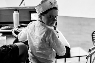 Vue depuis un bateau avec un siège orange au premier plan et un paysage côtier en arrière-plan.