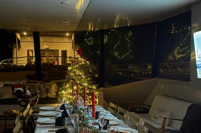 Vue depuis un bateau avec un siège orange au premier plan et un paysage côtier en arrière-plan.