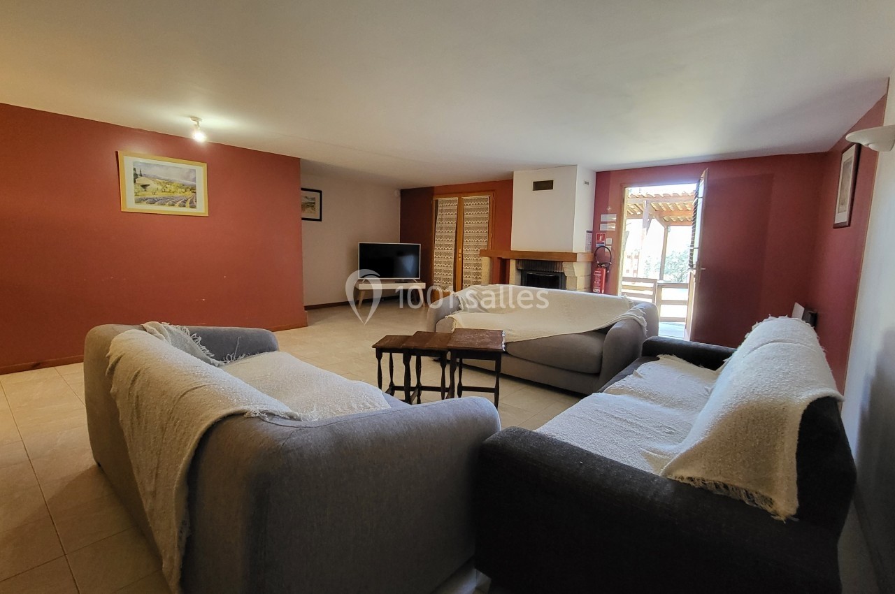 Salon spacieux avec trois canapés, table basse, télévision et cheminée, éclairé par une porte-fenêtre donnant sur l…