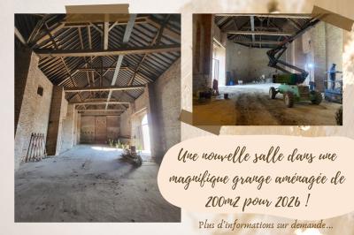 Miniature Location salle Esnes (Nord) - Domaine du Château d’Esnes #1 Pièce rustique avec murs en pierre, plafond en bois, réservoir métallique rouge et mobilier simple.